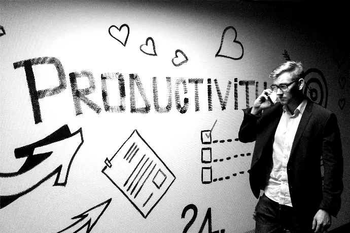 man holding smartphone looking at productivity wall decor